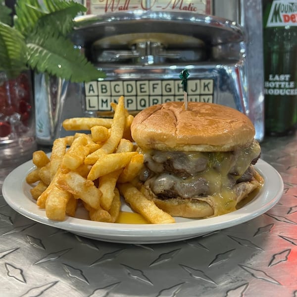 A double cheeseburger with melted cheese and a side of golden fries on a white plate at Southside Diner.