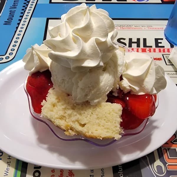 A strawberry shortcake with whipped cream and vanilla ice cream on a white plate at Southside Diner.