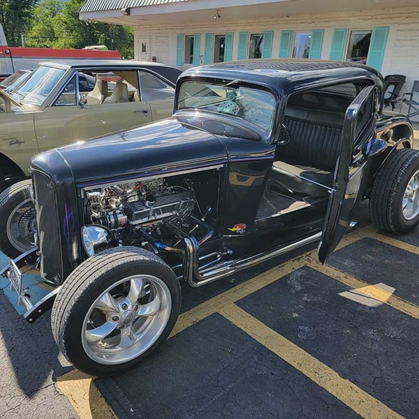 A black hot rod with an exposed engine and open door parked outside Southside Diner.
