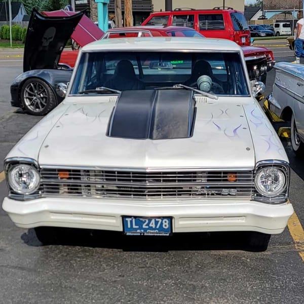 A white classic car with a black hood scoop and subtle flame decals parked at Southside Diner.