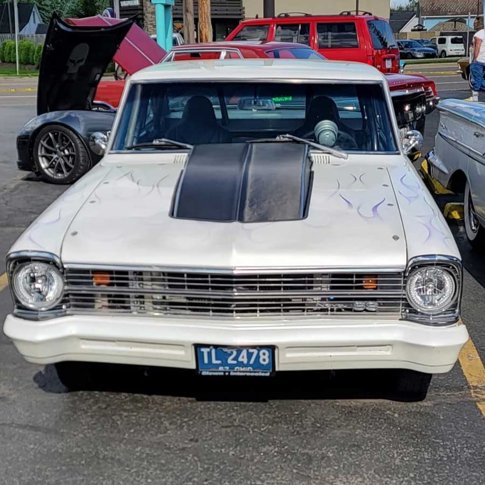 A white classic car with a black hood scoop and subtle flame decals parked at Southside Diner.
