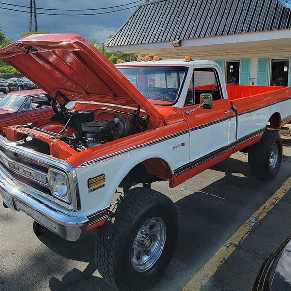A classic red and white pickup truck with its hood open, parked outside Southside Diner.