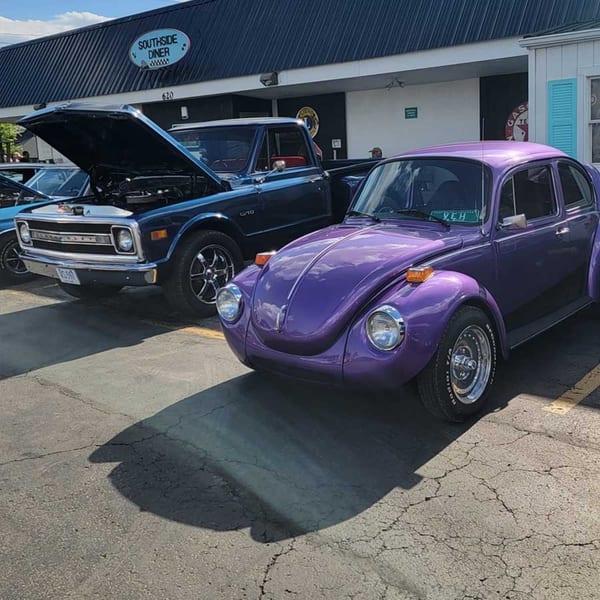 A purple Volkswagen Beetle and a blue pickup truck parked outside the Southside Diner.