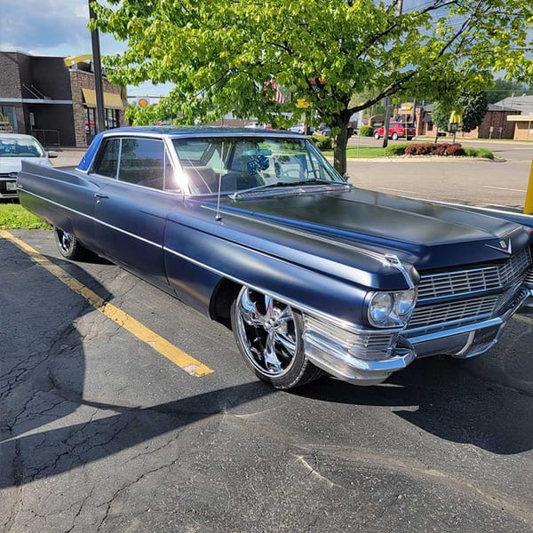 A classic dark blue Cadillac with chrome accents parked in a lot outside Southside Diner.
