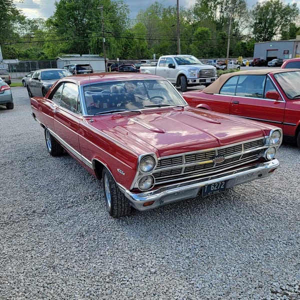 A shiny red vintage car with chrome details parked on a gravel lot at Southside Diner.